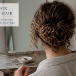 Curly hair gathered into a pinned bun with loose strands framing the face
