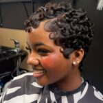 Woman showing a short, defined curly pixie haircut in a salon