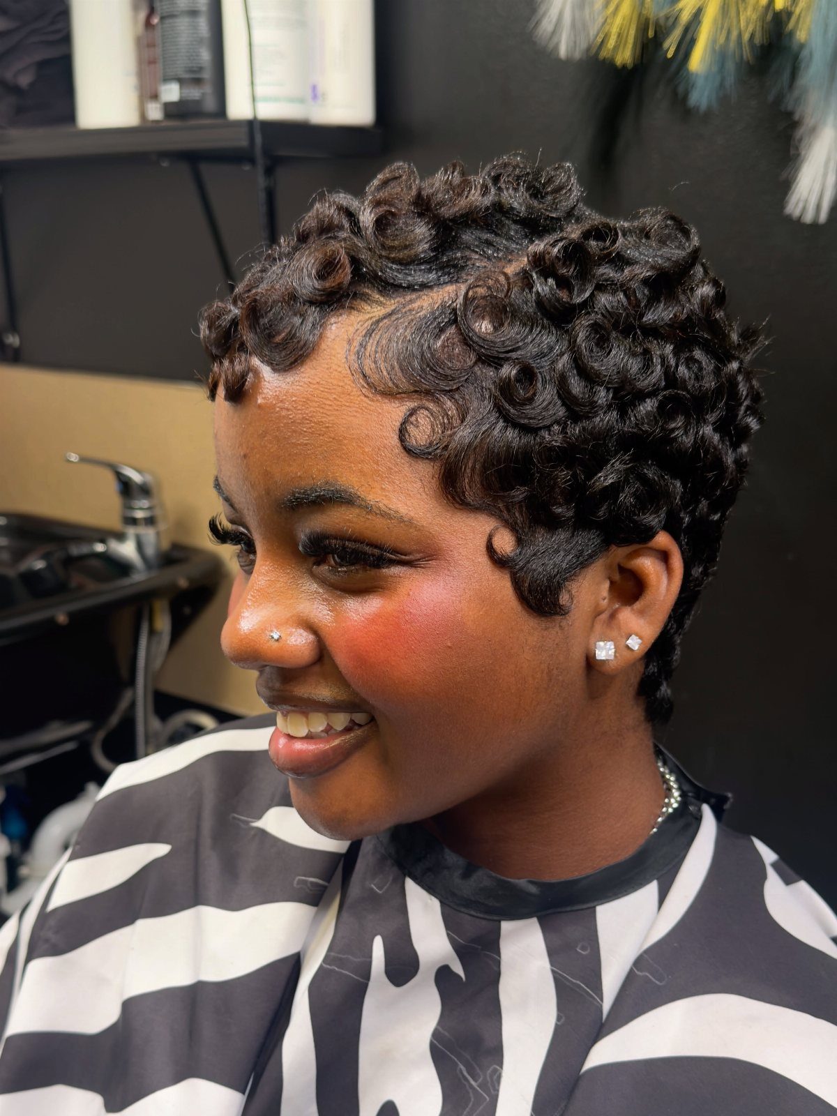 Woman showing a short, defined curly pixie haircut in a salon