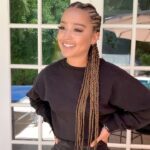 Woman displaying long brown feed-in braids woven close along her scalp