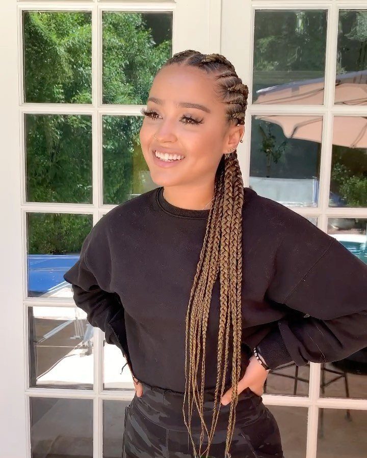 Woman displaying long brown feed-in braids woven close along her scalp