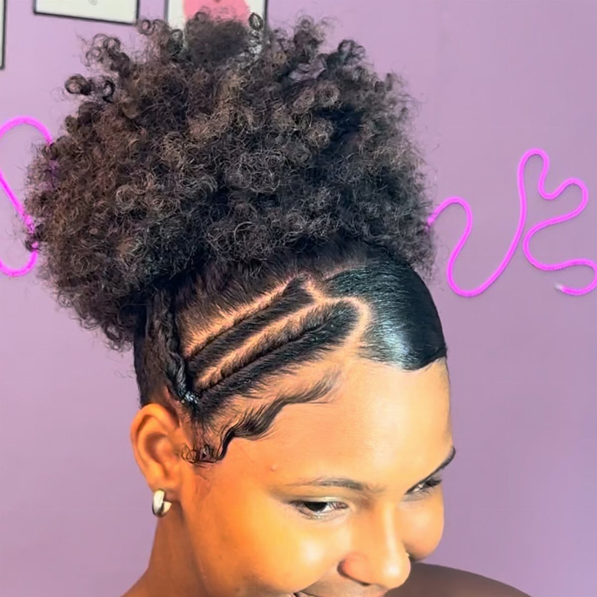 Curly-haired person showcasing a high puff with sleek patterned side styling