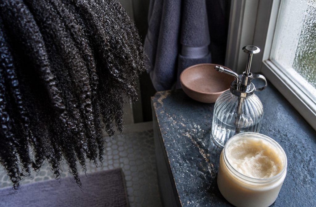 Natural coily hair with moisturized curls arranged against a simple background