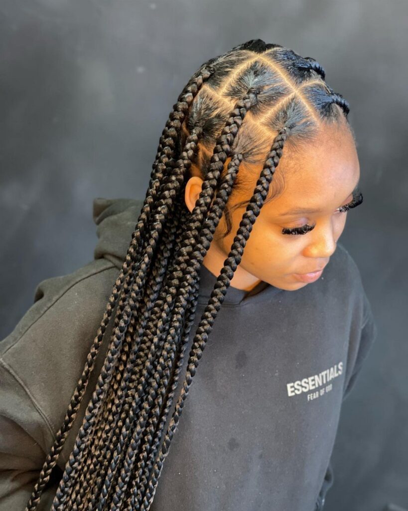 Long individual box braids with square partings drape over a woman's shoulder