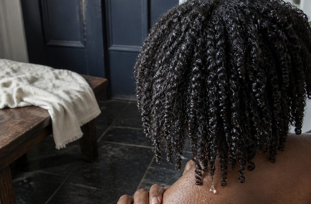 Woman with defined 4c coils shown from behind in a loose wash-and-go style