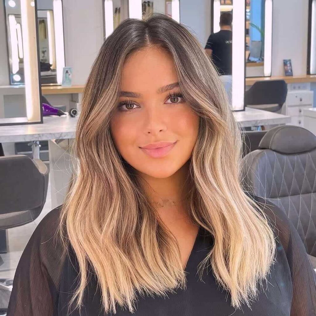 Woman showcasing medium-length wavy blonde hairstyle in a bright salon