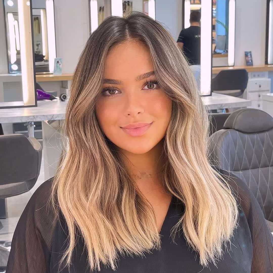 Woman showcasing medium-length wavy blonde hairstyle in a bright salon